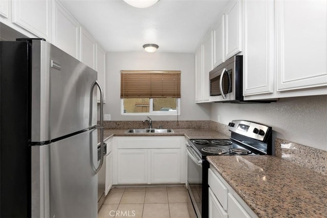 kitchen featuring white cabinets, stainless steel appliances, a sink, and light tile patterned floors
