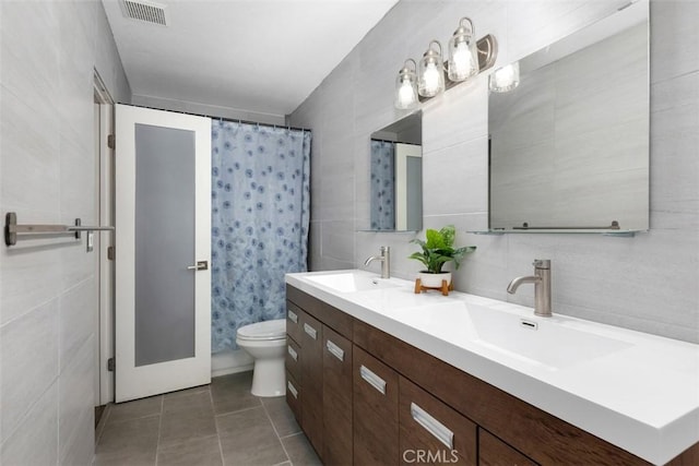 bathroom with visible vents, a sink, double vanity, and toilet