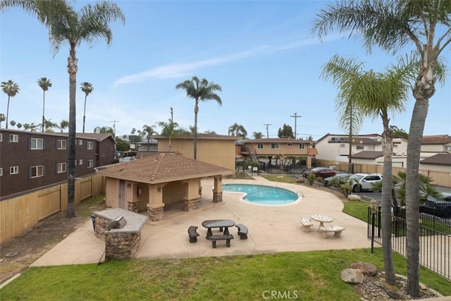 pool with fence, a lawn, a residential view, and a patio