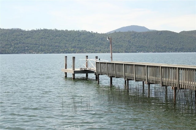 dock area with a water and mountain view and a wooded view