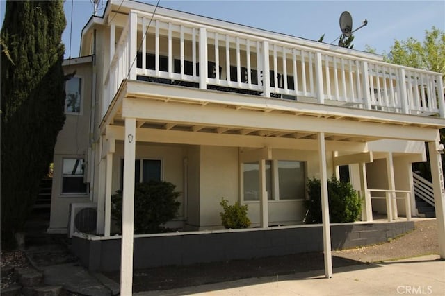 rear view of property with stucco siding and a balcony