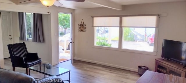 living room with beamed ceiling, baseboards, a ceiling fan, and wood finished floors