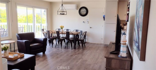 dining space with a wall mounted air conditioner and light wood-style flooring