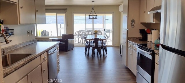 kitchen with under cabinet range hood, a wealth of natural light, appliances with stainless steel finishes, and wood finished floors