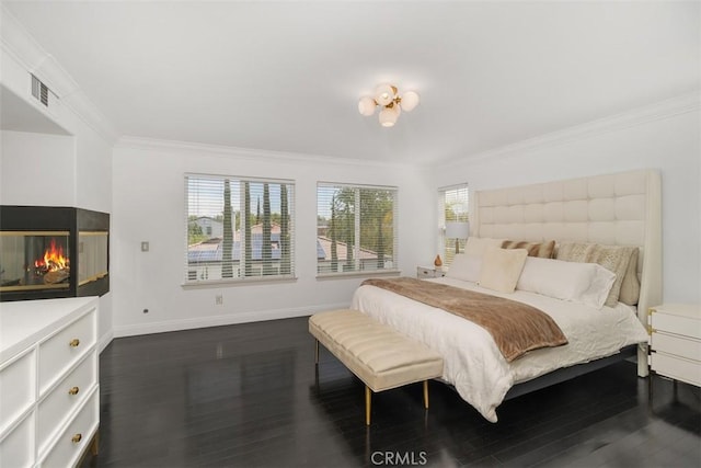 bedroom with dark wood-style flooring, a multi sided fireplace, baseboards, visible vents, and ornamental molding