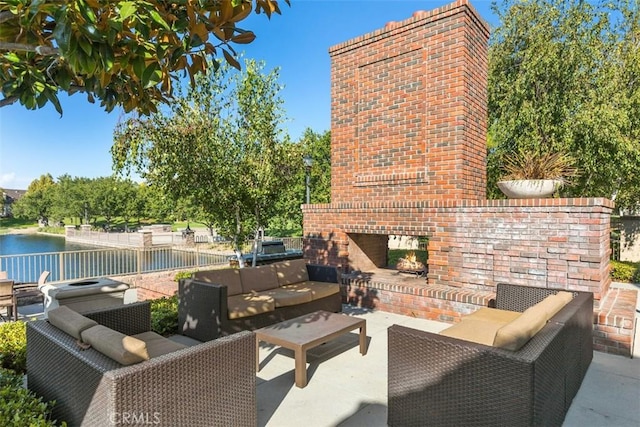 view of patio featuring fence, an outdoor living space with a fireplace, and a water view