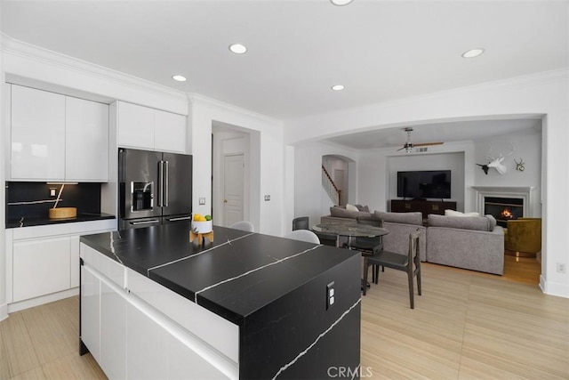 kitchen featuring high end refrigerator, arched walkways, a kitchen island, and recessed lighting