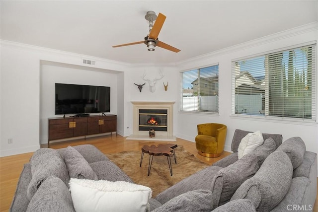 living area featuring ornamental molding, a ceiling fan, wood finished floors, and visible vents