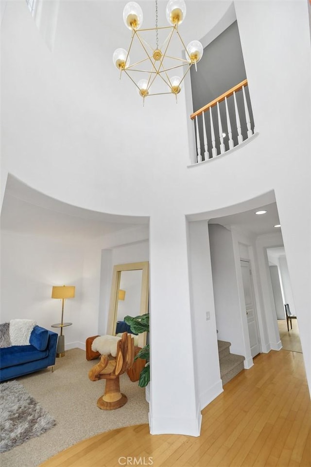 living room featuring an inviting chandelier, stairs, a towering ceiling, and wood finished floors