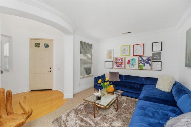 living room with crown molding, baseboards, wood finished floors, and visible vents