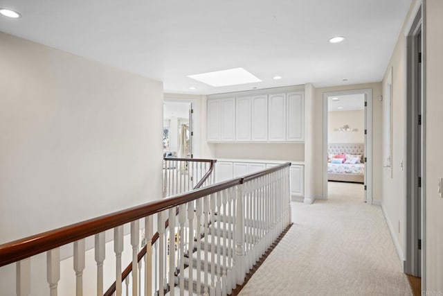 hallway featuring recessed lighting, an upstairs landing, a skylight, baseboards, and light colored carpet