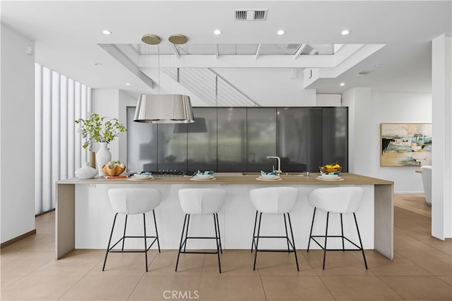 9 Temple Ave, Long Beach, CA 90803 - kitchen featuring recessed lighting, visible vents, light tile patterned floors, a sink, and a breakfast bar area