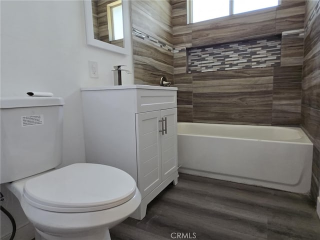 full bathroom with a bathing tub, toilet, wood finished floors, and vanity