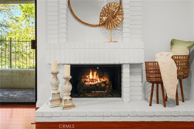 details featuring a brick fireplace and wood finished floors