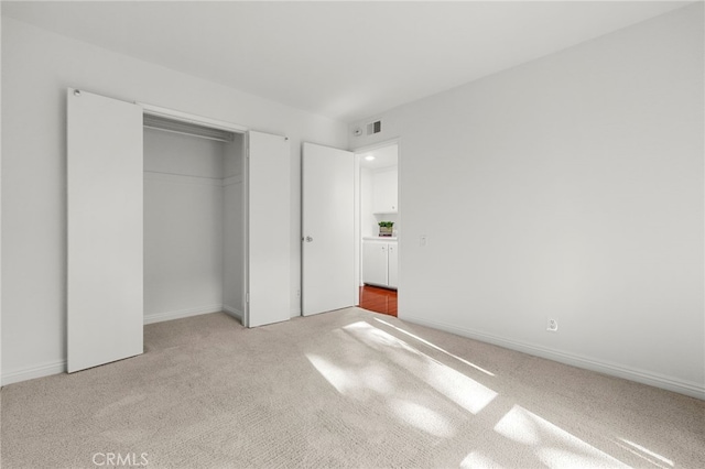 unfurnished bedroom featuring baseboards, light carpet, and a closet