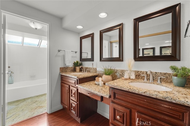 full bathroom with double vanity, wood finished floors, bathtub / shower combination, and a sink