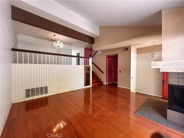 7 Wilderness Pl, Pomona, CA 91766 - unfurnished living room featuring a chandelier, vaulted ceiling, wood finished floors, a tiled fireplace, and stairs