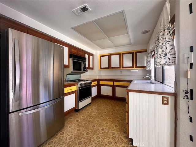 7 Wilderness Pl, Pomona, CA 91766 - kitchen featuring freestanding refrigerator, black microwave, white gas stove, tile countertops, and a sink