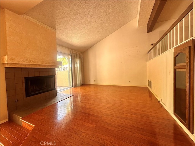 7 Wilderness Pl, Pomona, CA 91766 - unfurnished living room with lofted ceiling, hardwood / wood-style flooring, a textured ceiling, and a tile fireplace