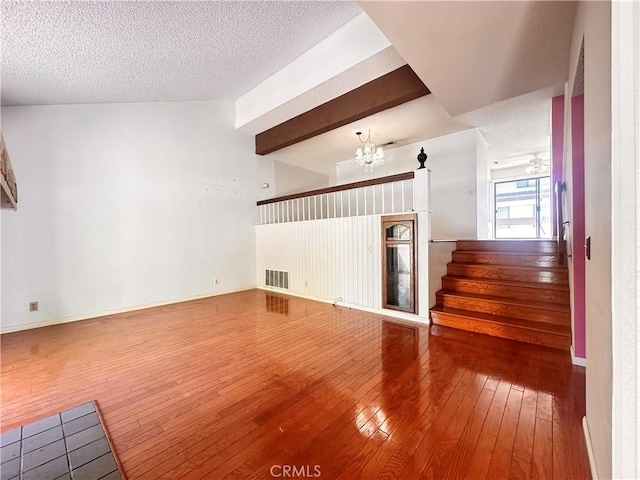 7 Wilderness Pl, Pomona, CA 91766 - unfurnished living room featuring hardwood / wood-style floors, a chandelier, a textured ceiling, stairway, and baseboards