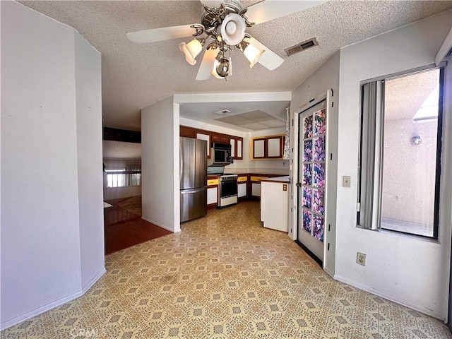 7 Wilderness Pl, Pomona, CA 91766 - kitchen with gas range oven, freestanding refrigerator, black microwave, baseboards, and ceiling fan