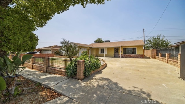 ranch-style home with driveway, a fenced front yard, and stucco siding