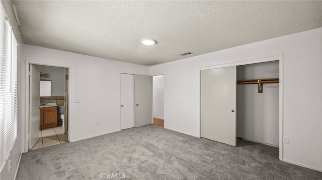 unfurnished bedroom with carpet, a textured ceiling, and ensuite bath