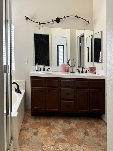 1380 Riverstone Ct, Hemet, CA 92545 - bathroom featuring a bath, a sink, double vanity, and a stall shower