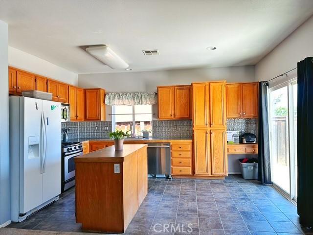 1380 Riverstone Ct, Hemet, CA 92545 - kitchen with visible vents, decorative backsplash, stainless steel appliances, and a healthy amount of sunlight