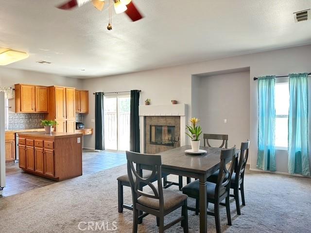 1380 Riverstone Ct, Hemet, CA 92545 - carpeted dining room featuring tile patterned flooring, a tile fireplace, visible vents, and a ceiling fan
