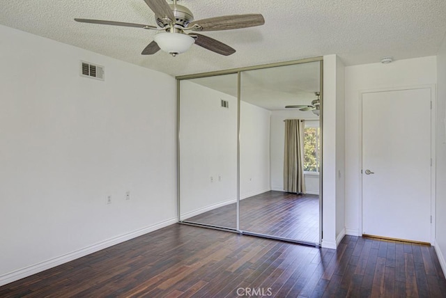 unfurnished bedroom with wood finished floors, visible vents, a closet, baseboards, and a textured ceiling