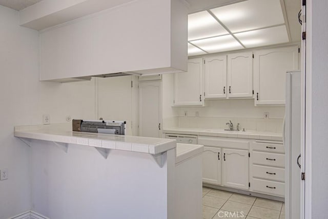 kitchen with white cabinets, a peninsula, tile countertops, and light tile patterned floors