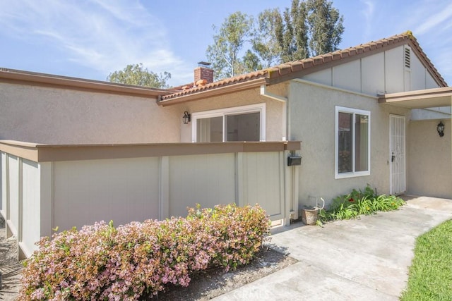 view of front of house with a chimney, stucco siding, and fence