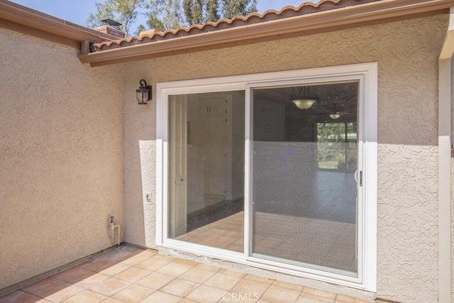 property entrance featuring a tiled roof and stucco siding