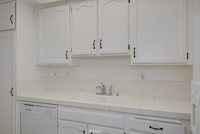 kitchen featuring dishwasher, white cabinetry, tile counters, and a sink