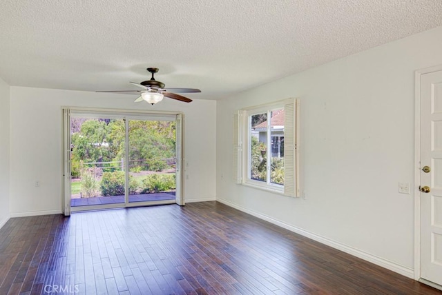 spare room featuring dark wood finished floors, a wealth of natural light, a ceiling fan, and baseboards