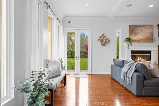 interior space featuring wood finished floors, a glass covered fireplace, french doors, beamed ceiling, and baseboards