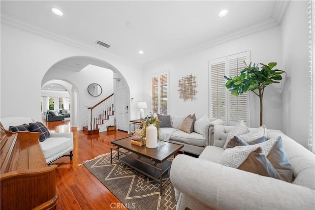 living area with arched walkways, visible vents, crown molding, and a wealth of natural light