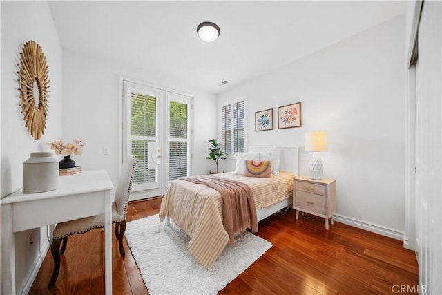 bedroom featuring baseboards, wood finished floors, access to exterior, and visible vents
