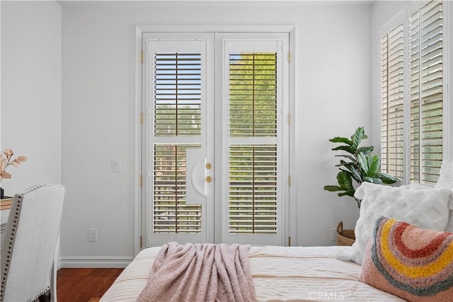 bedroom with wood finished floors, baseboards, and access to outside