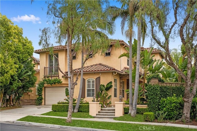 mediterranean / spanish house with stucco siding, a tile roof, driveway, and a garage