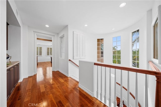 hallway featuring baseboards, dark wood-style floors, and an upstairs landing
