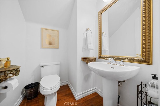 half bath featuring baseboards, wood finished floors, and toilet