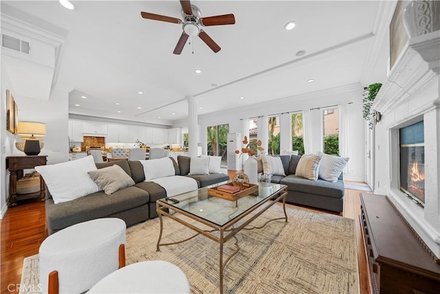 living room with a glass covered fireplace, ceiling fan, light wood finished floors, visible vents, and recessed lighting