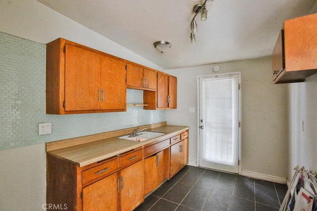 643 W Ramona Dr, Rialto, CA 92376 - kitchen featuring dark tile patterned floors, light countertops, decorative backsplash, brown cabinets, and lofted ceiling