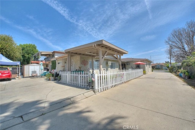 view of front of property featuring concrete driveway, an outdoor structure, a storage shed, and a fenced front yard