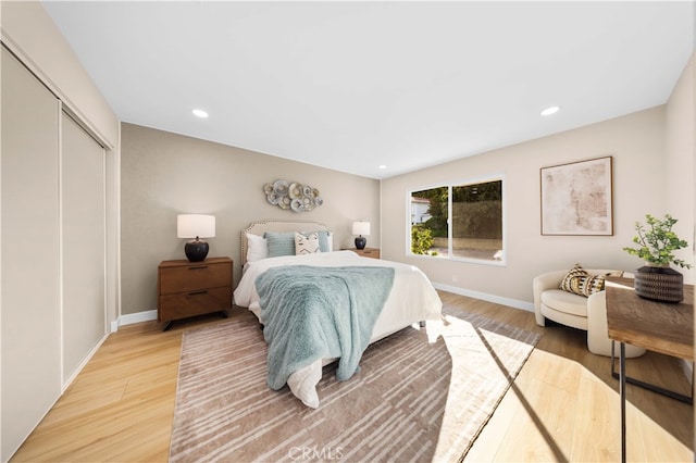 bedroom featuring baseboards, recessed lighting, light wood-style floors, and a closet