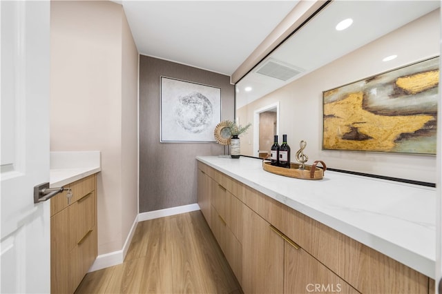 interior space with baseboards, visible vents, vanity, and wood finished floors