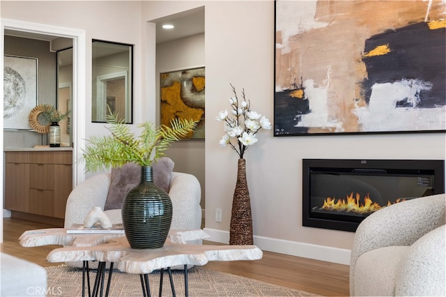 interior space with a glass covered fireplace, wood finished floors, and baseboards