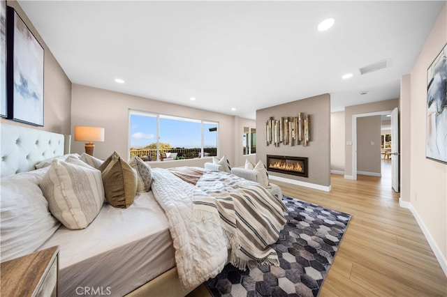 bedroom with baseboards, recessed lighting, visible vents, light wood-style floors, and a large fireplace